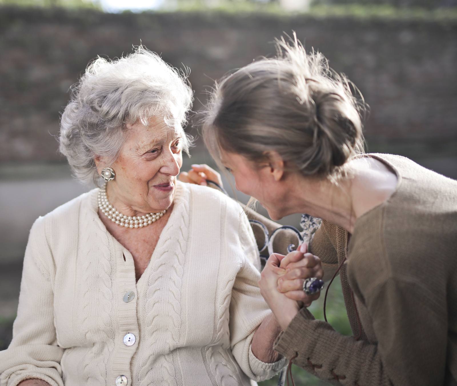 An older woman and her daughter talking together in a garden
